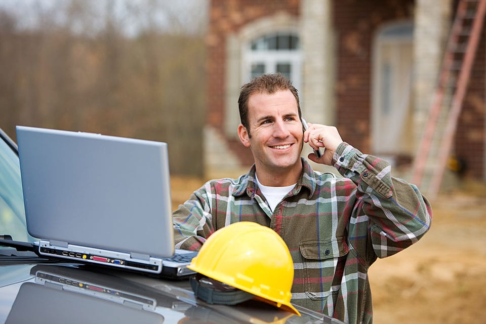 Construction: Builder on mobile phone outside of job site