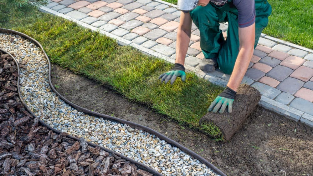 image of landscaping contractor rolling out sod