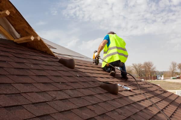 roofer nailing shingles to a roof