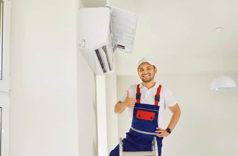 Portrait of smiling male technician showing thumb up after commissioning air conditioner