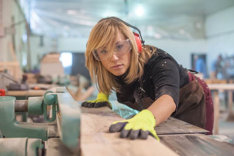Female carpenter Using Electric Sander for wood
