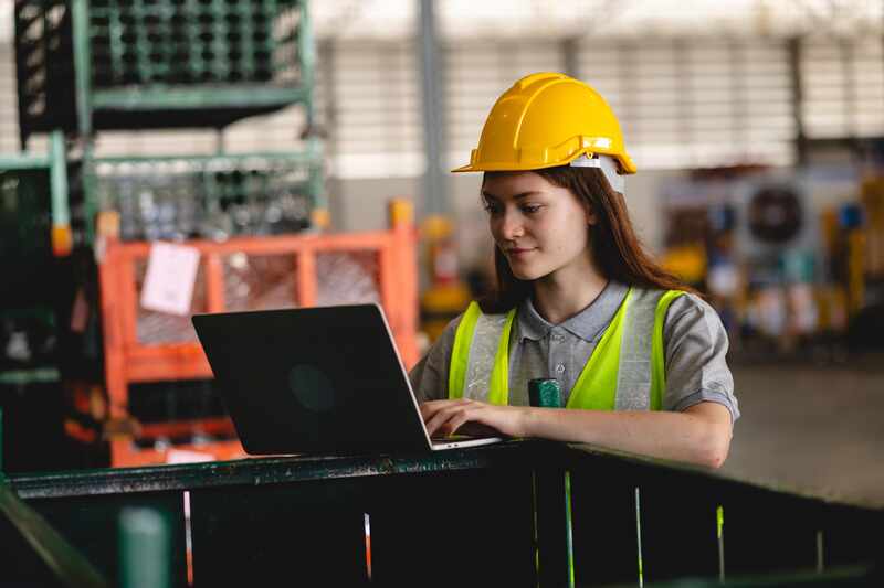 Female worker with safety helmet using laptop
