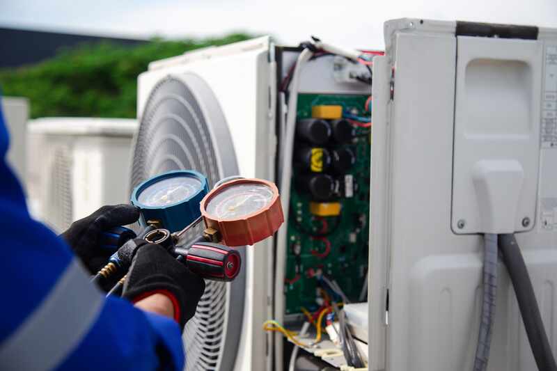 air conditioner technician using a gauge to measure the refrigerant pressure air compressor