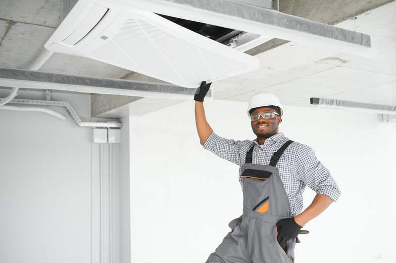 low angle view of African American handyman repairing air conditioner