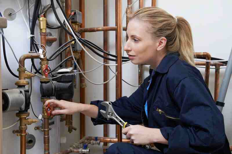 Female Plumber Working On Heating Boiler