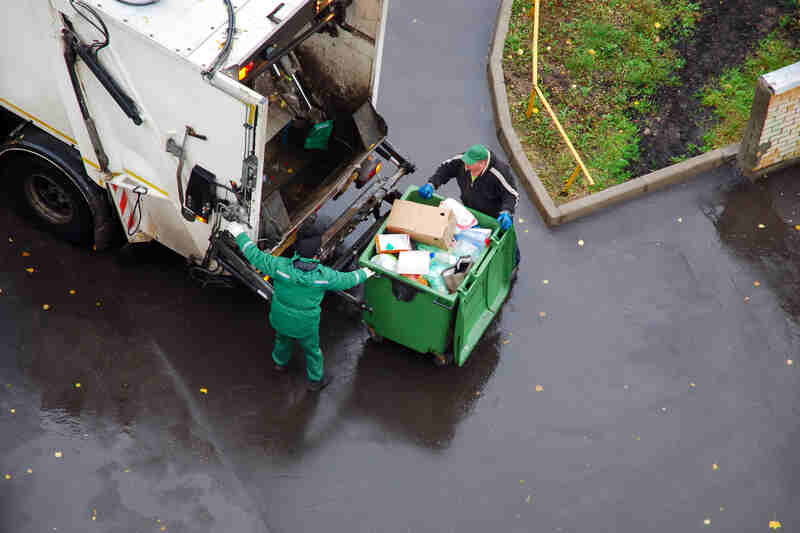 garbage men loading junk in garbage truck