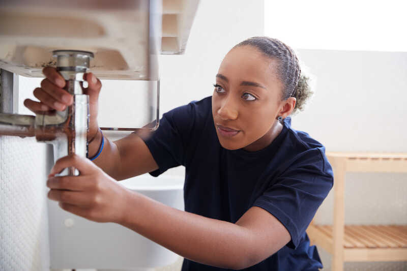 Female Plumber Working To Fix Leaking Sink