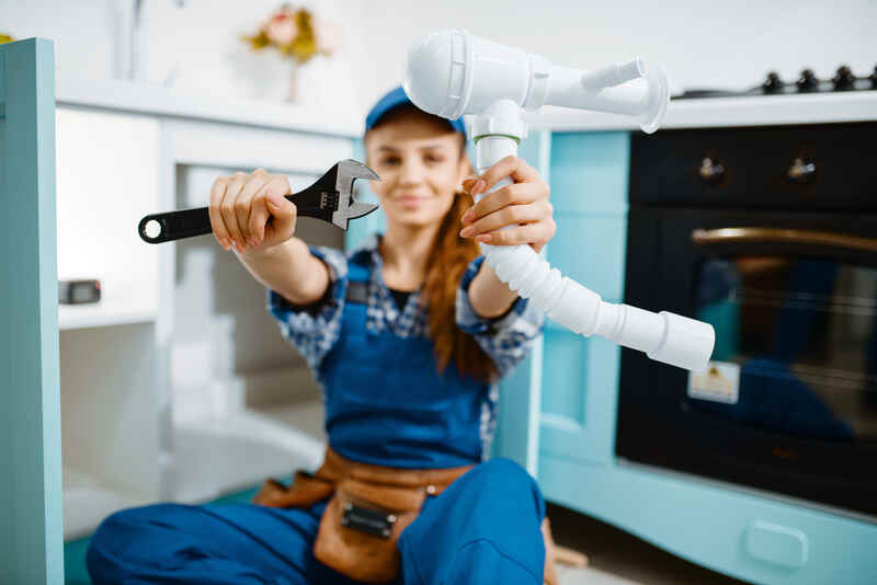 Young female plumber working with tools wrench and pipe