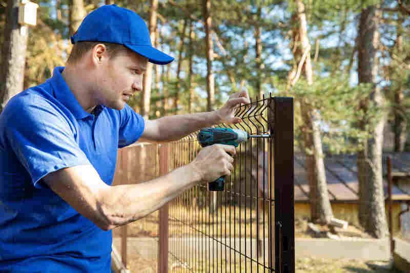 worker installing welded metal mesh fence