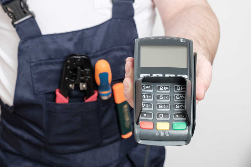 Man with tools holding bank payment terminal
