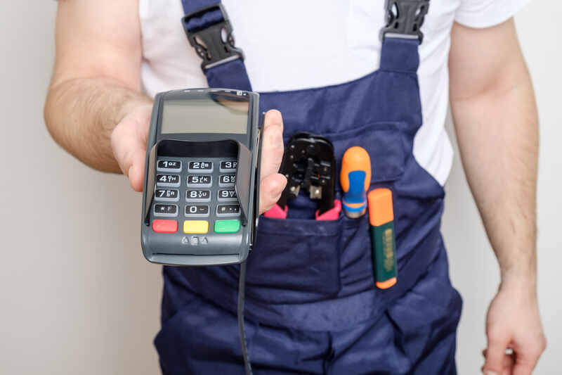 Man with tools holding bank payment terminal