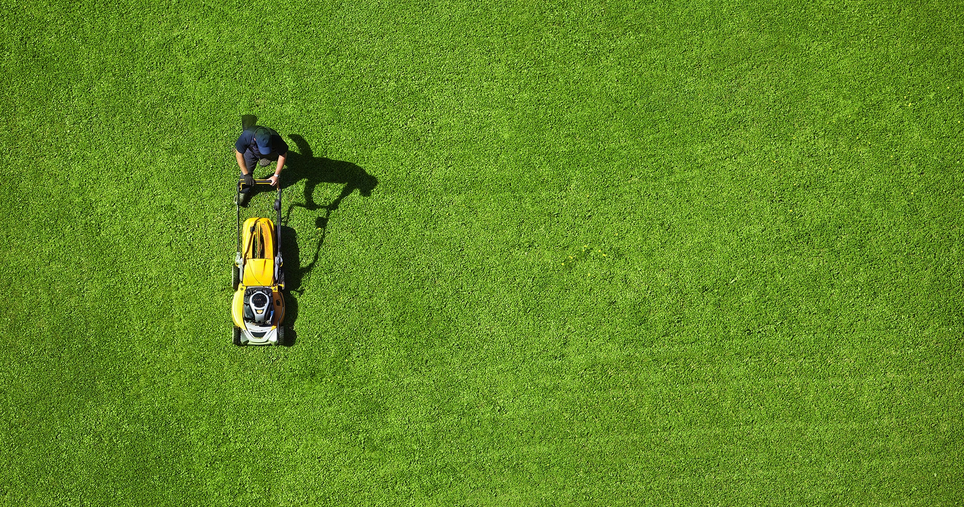 Aerial view of landscaping pro mowing large green lawn