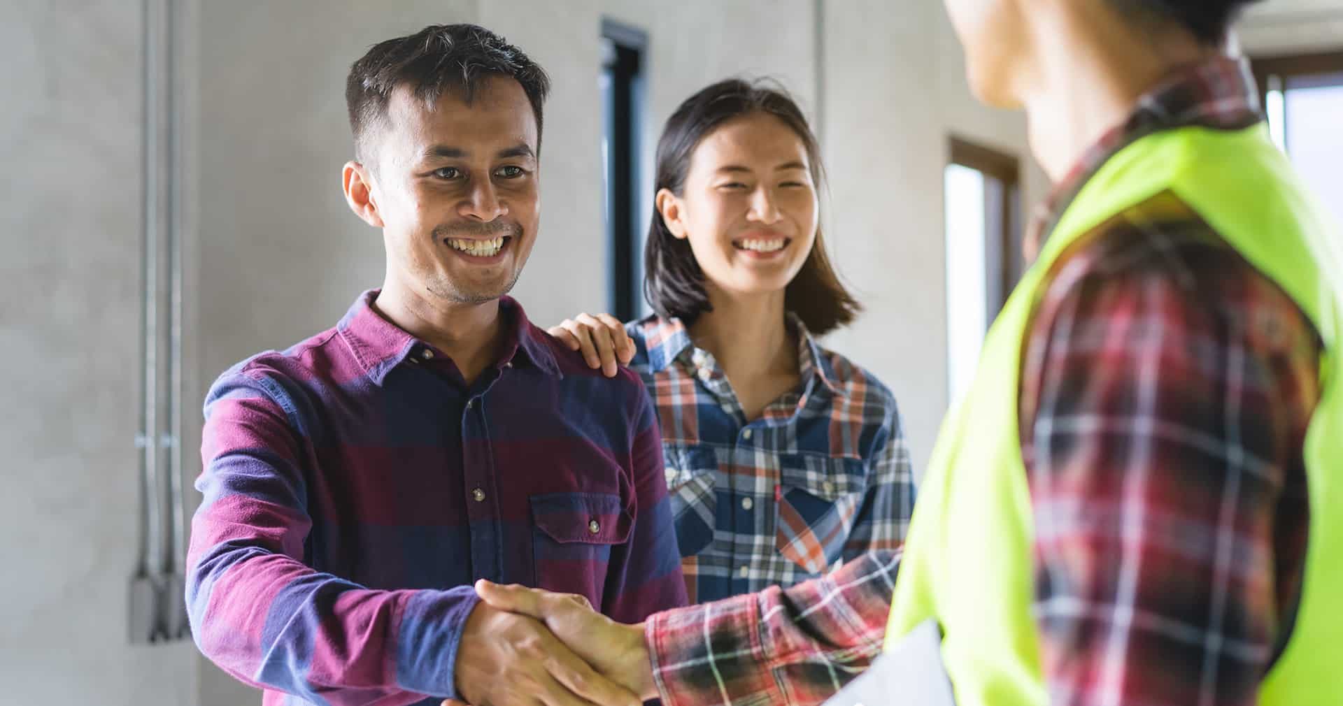 Clients smiling and shaking hands with contractor