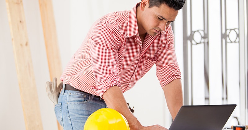 Contractor at jobsite on laptop