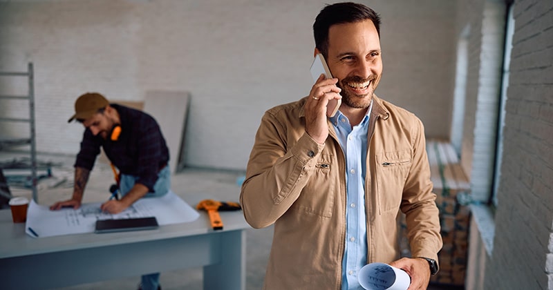 Home remodeling pro on phone with colleague in background