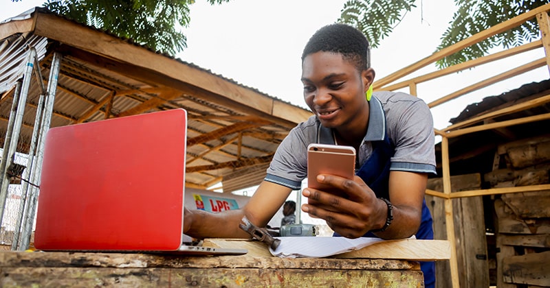 Carpenter working outside with open laptop and mobile phone