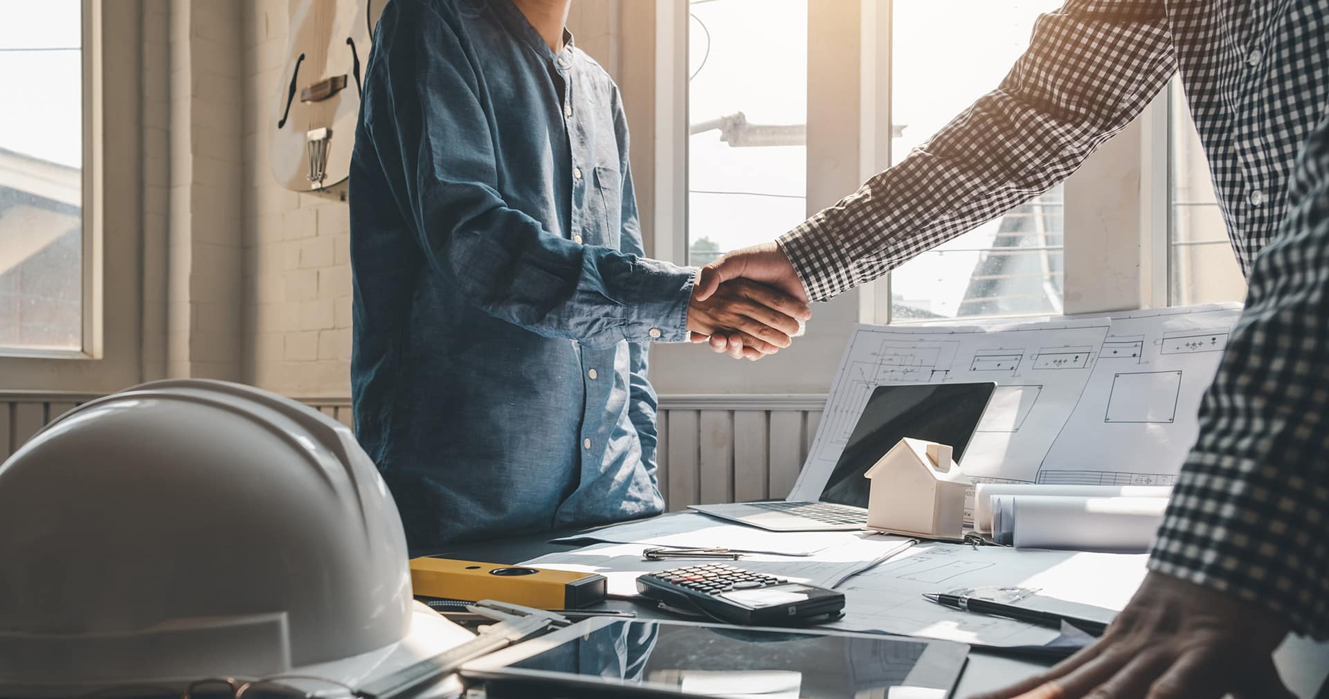 Client and contractor shaking hands in home office