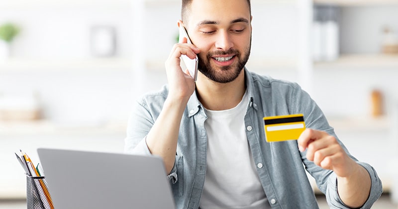 Client makes credit card payment over the phone with open laptop in front