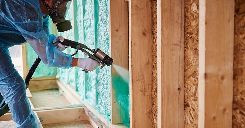 Contractor insulating wooden frame house with polyurethane foam