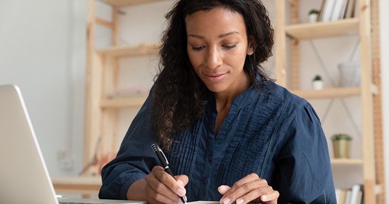 Customer writing a check in front of open laptop