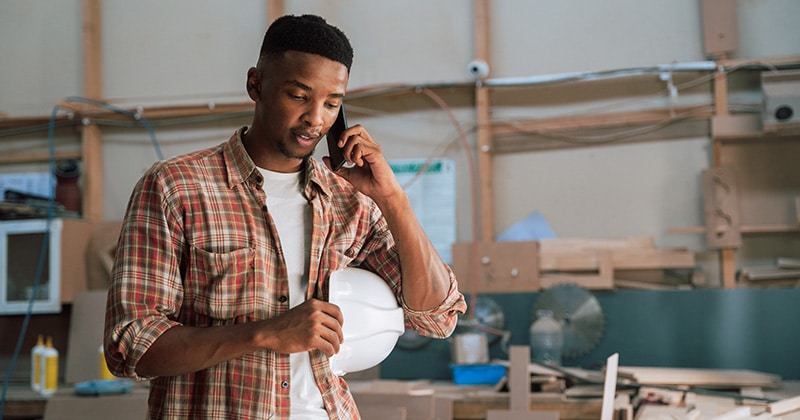 Home pro on phone with client in carpentry workshop