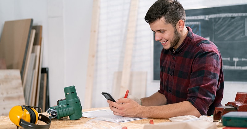 Carpenter uses smartphone in workshop