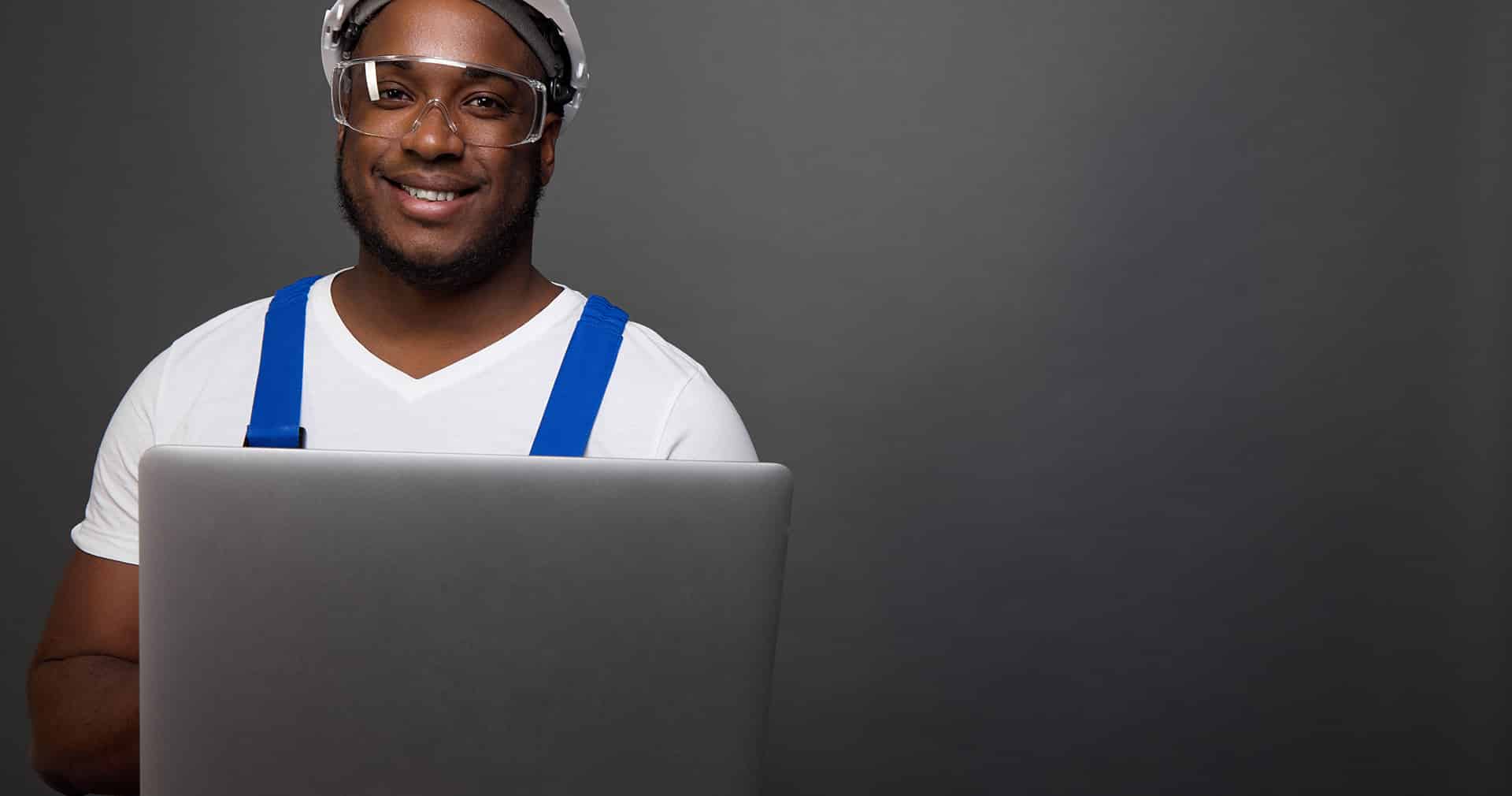 Construction pro holds laptop and smiles at camera
