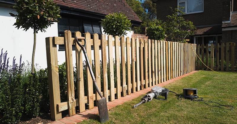 Installation of a wooden picket fence with tools visible