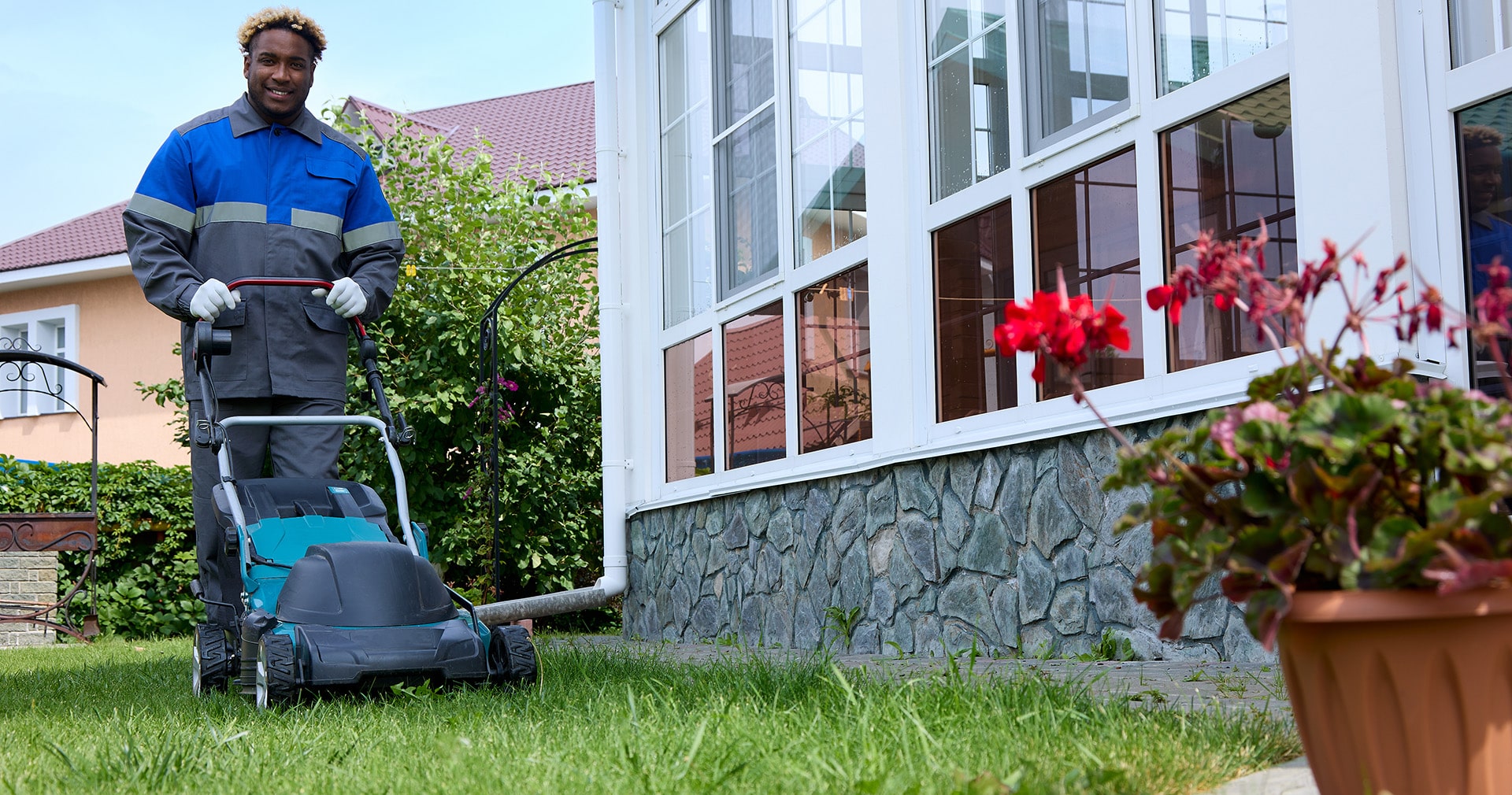 Landscaping contractor pushes lawn mower in backyard