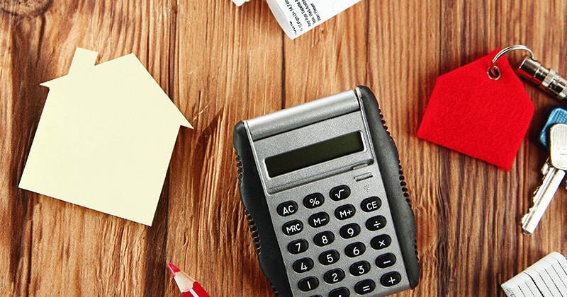 Cost estimation concept with calculator mini house and sketch on wooden table