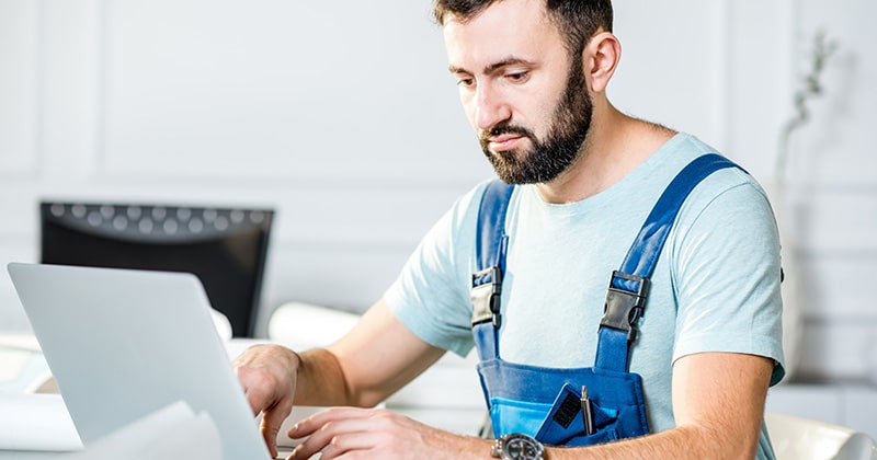 Electrical contractor works on electrical bid on laptop