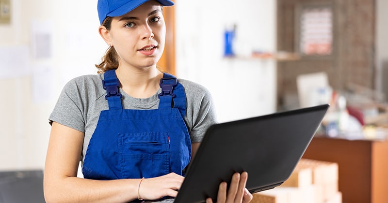 Electrician in blue hat holding laptop at building site