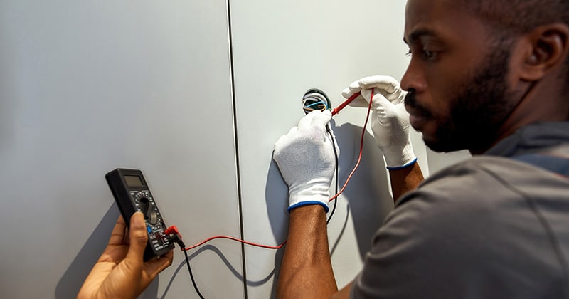Electrician with multimeter checking socket