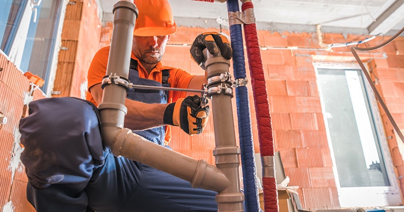Plumber installs pipe in commercial building