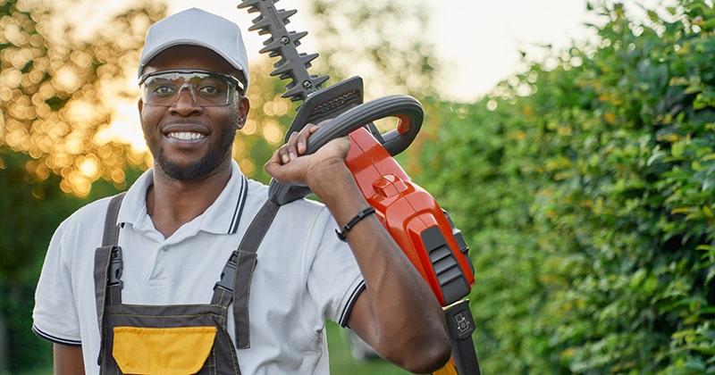 Smiling lawn care pro with hedge trimmer