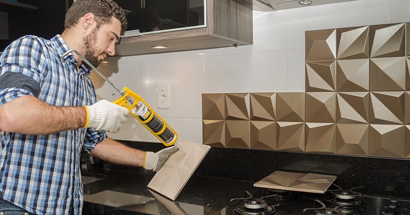 Contractor installs tile on kitchen wall