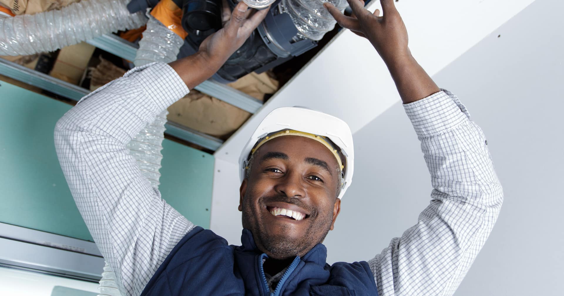 Technician installing AC unit in overhead space