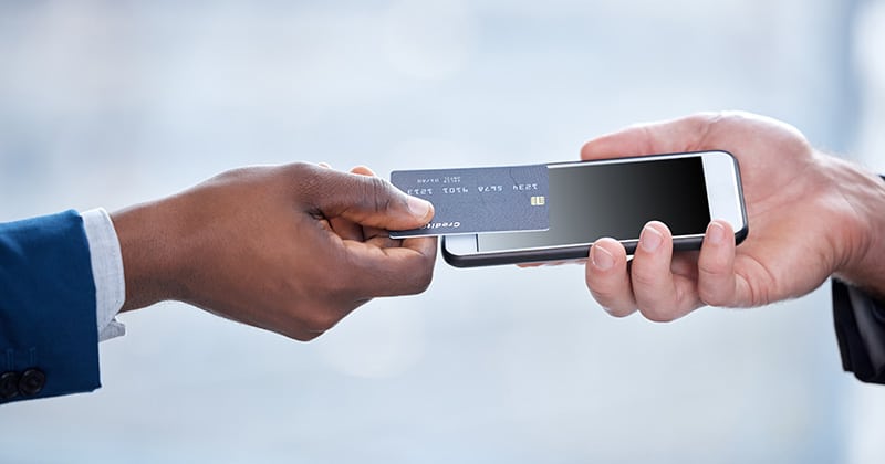 Close up of hands using card to Tap to Pay on phone
