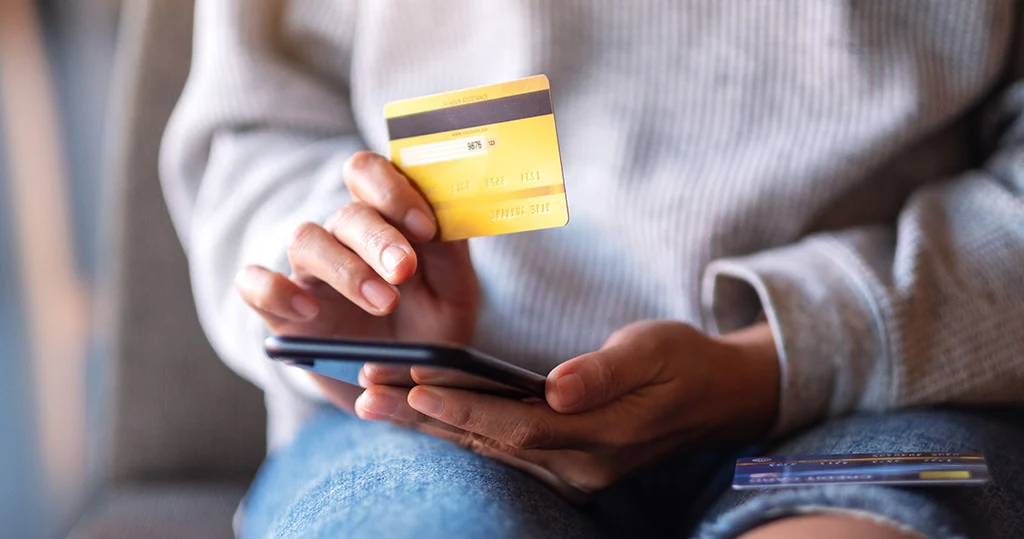 Closeup of person using credit card to checkout on mobile phone