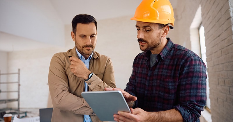 Contractor and homeowner reviewing tablet at construction site
