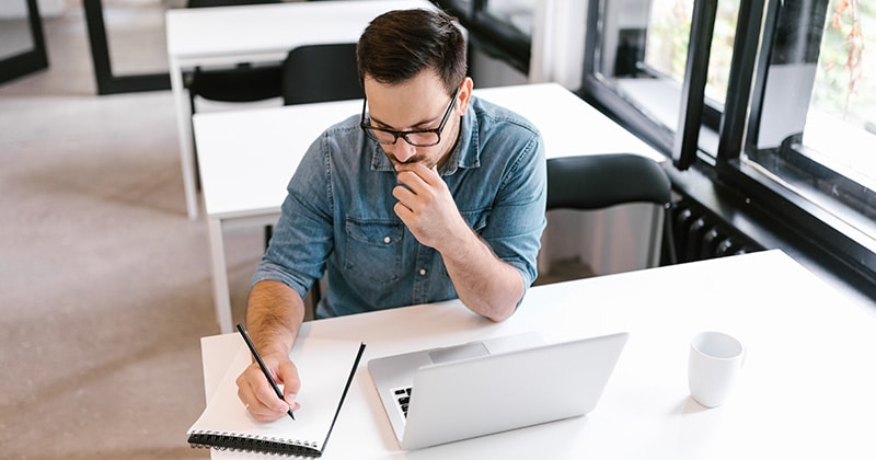 Contractor studying for test with notebook and laptop