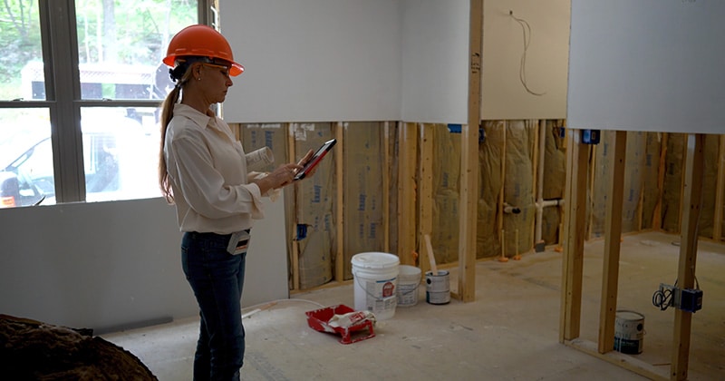 Contractor walks through home construction project with tablet