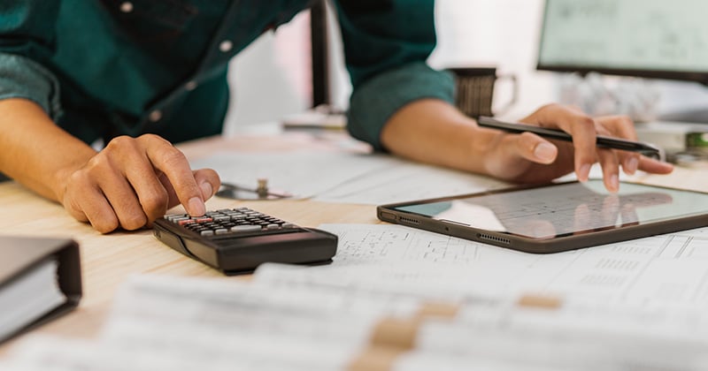 Contractor with blueprints, calculator, and tablet