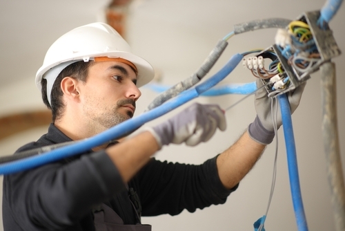 Electrician working to install an electrical system in a house being renovated.