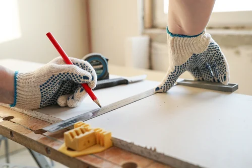 General contractor measures and marks drywall sheet
