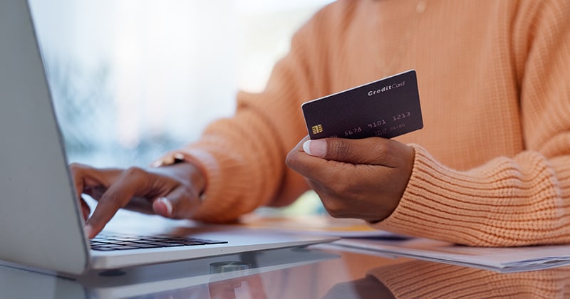 Hands of woman with credit card, making payment on laptop