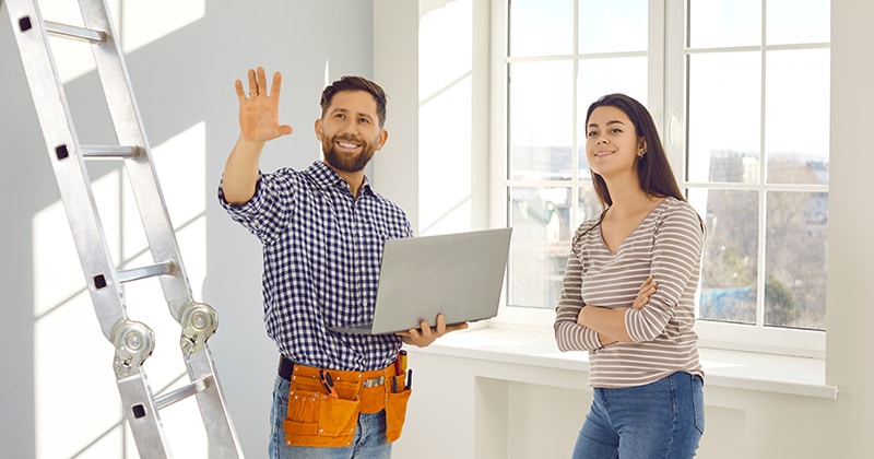 Home contractor holding laptop discusses project with homeowner