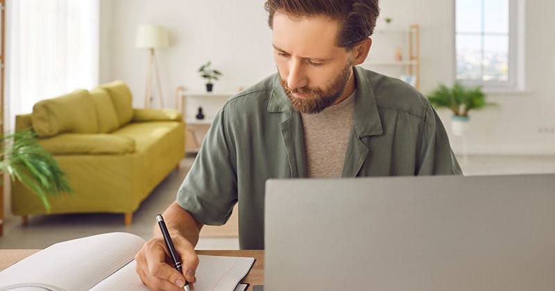 Home contractor taking note in front of open laptop
