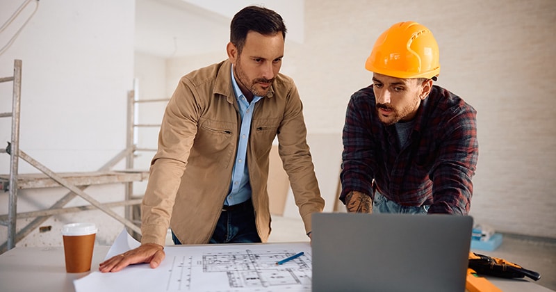 Homeowner and contractor onsite look at laptop together