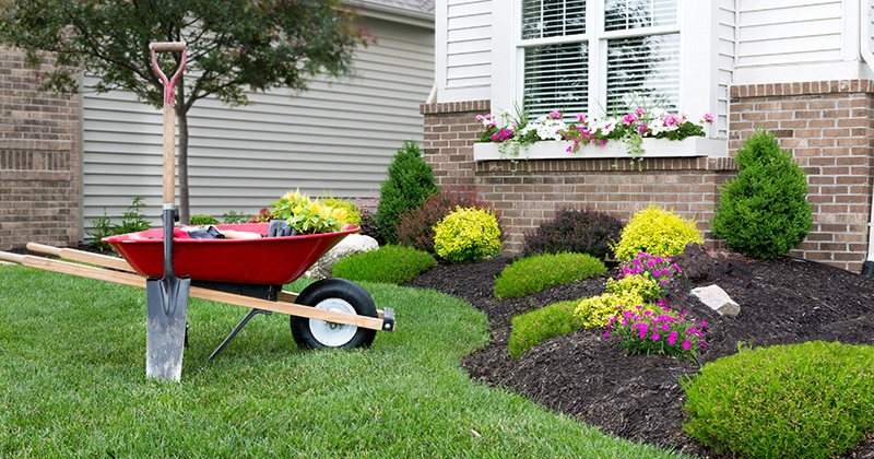 Landscaping tools around a garden bed in front of a house
